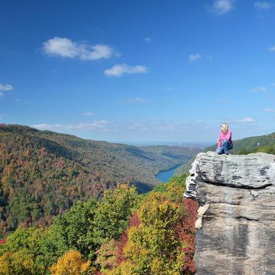 Scenic view of person in a pink shirt sitting on the Coopers Rock outlook in West Virginia.