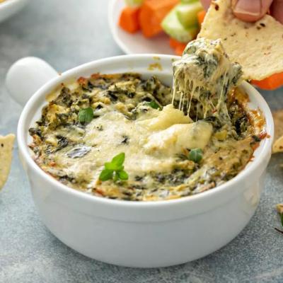 Artichoke spinach dip in a baking dish with a cheese pull.