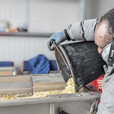 A LeftCoast worker pouring a bucket of discarded shells into a machine.