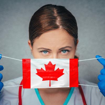 A female nurse putting on a mask printed with a Canadian flag.