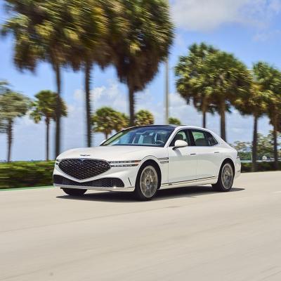 White Genesis G90 on the road with palm trees and sky in the background.