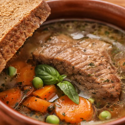 Crock pot with stewed meat and vegetables with a slice of bread