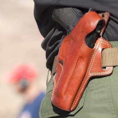 Gun in brown leather holster on belt.