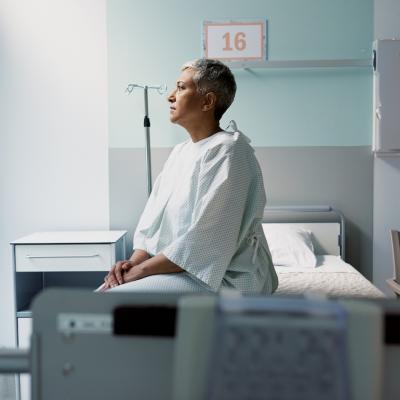 A patient with cancer sits on their hospital bed.