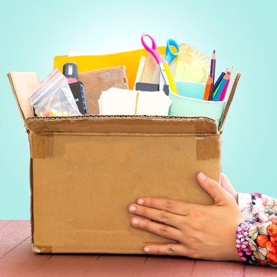 A teacher's hands holding a box of school supplies.