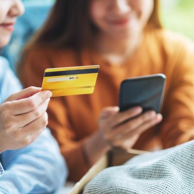 Two women happily looking at a phone and credit card.