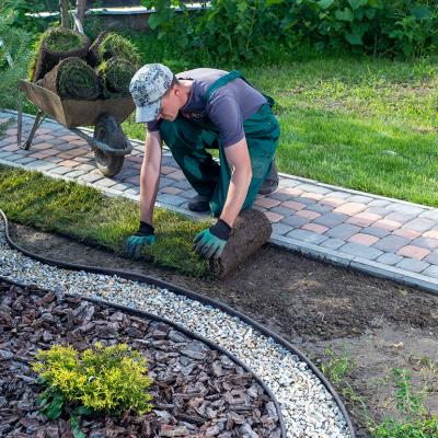 A landscaper doing maintenance on a lawn curb.