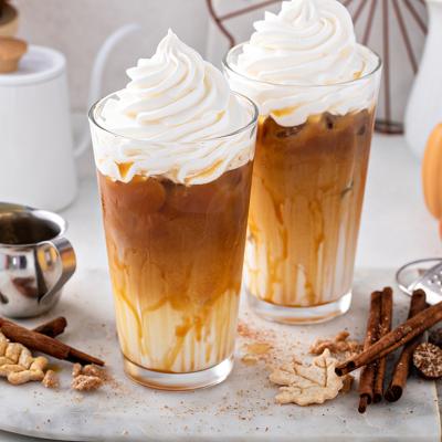 Two glasses of pumpkin spice lattes surrounded by its common ingredients.