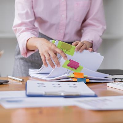 A professional stacking piles of business documents and reports.