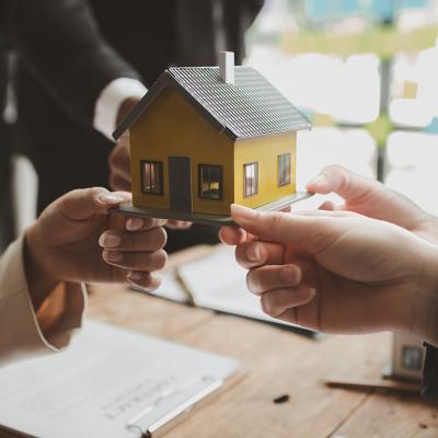 A conceptual image showing three people holding a house figure to represent investing in a real estate.