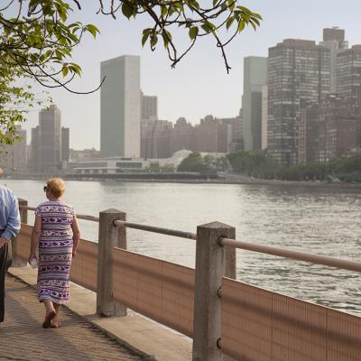 A senior couple walking along a park path in New York City.