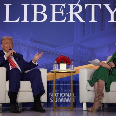 On stage, Donald Trump speaks as Co-founder of Moms for Liberty Tiffany Justice looks on during the 2024 Joyful Warriors National Summit on August 30, 2024 in Washington, DC.