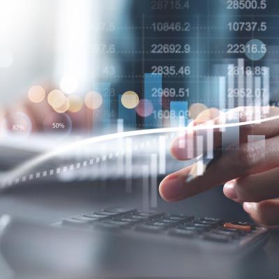 Calculating taxes concept, close up of person doing finances and on calculator with graphs superimposed in foreground.