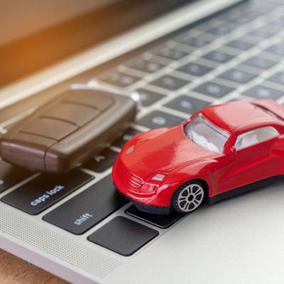 A figure of a red car and car key on top of a laptop.