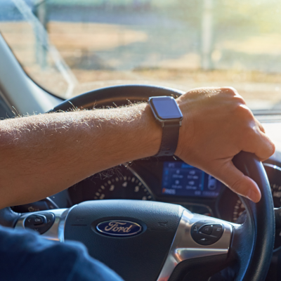 Close-up of a person’s arm gripping the steering wheel of a Ford car.