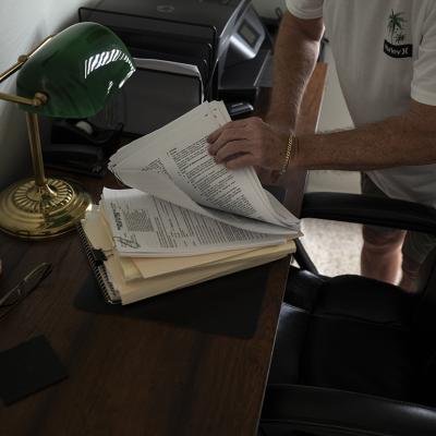 A senior Florida homeowner flips through insurance documents after his home is damaged by a hurricane.