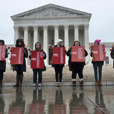 Activists protesting the death penalty holding up names on red signs in front of the U.S. Supreme Court.