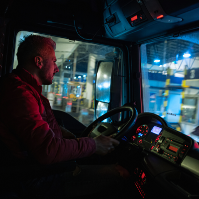 A driver steers behind the wheel of a truck at night.