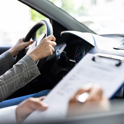 A female driver taking driving lessons with an instructor inside the car.