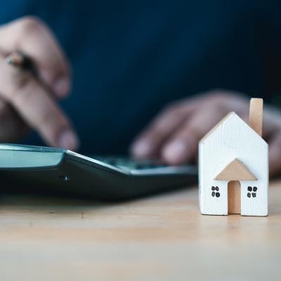 Person calculating interest rates with a house figure on the side.