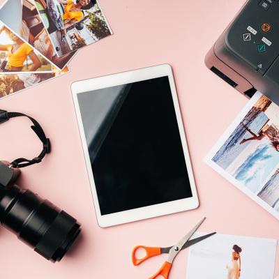 A flatlay of gadgets such as a photo camera, tablet, and printer used to archive digitally.