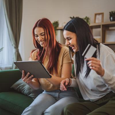 Two Gen Z women browsing online using a tablet and using a credit card.