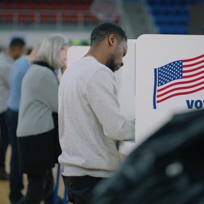 Male voter with bulletin in hands comes to a voting booth on US election day. 