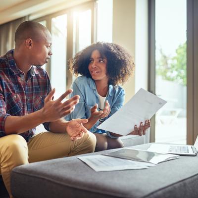 Two people discussing financial paperwork looking confused.