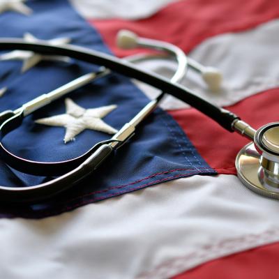 Conceptual image of American healthcare where a stethoscope is on top of a U.S. flag.