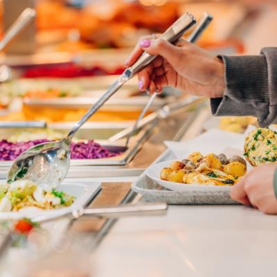 Person puts food on their plate at a buffet.