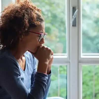 Person sitting by their window, looking sad and depressed.