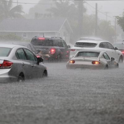 Cars are parked in a flooded street in Dania Beach, FL.