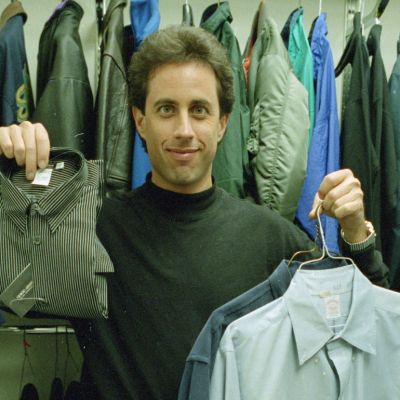 Jerry Seinfeld standing in a closet holding up clothes