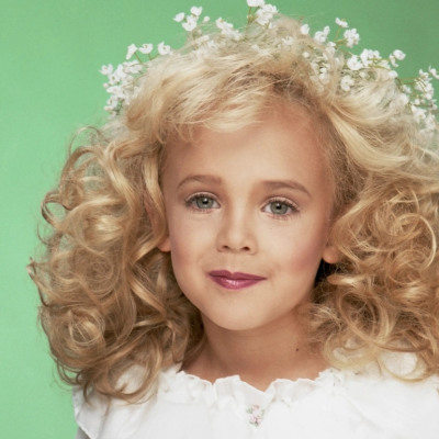 A portrait still of JonBenet Ramsey against a green background