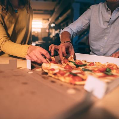 Two people having pizza at night.