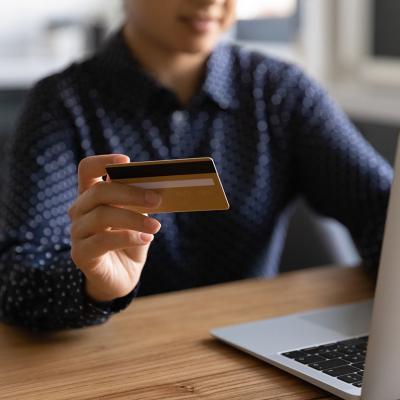 A business professional using a credit card and a laptop.