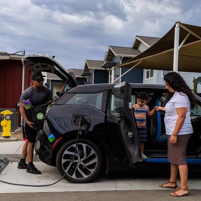 A family of three getting items ready inside a charging electric vehicle.