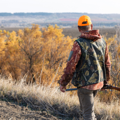 Hunter walking carrying a rifle on a sunny fall day