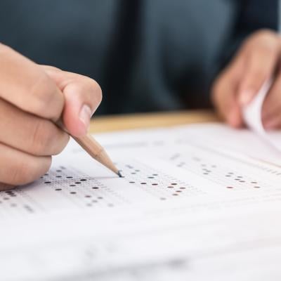 Closeup of student holding a pencil and taking standardized test.