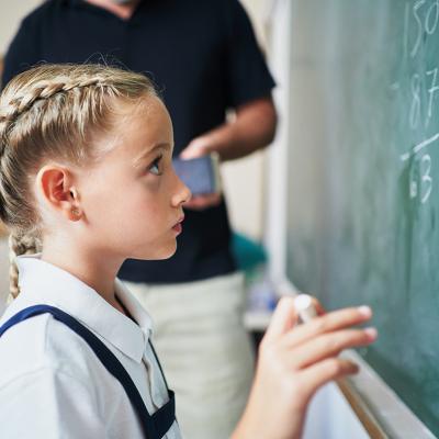 A young girl answering a mathematical exercise using the board in front of a class.