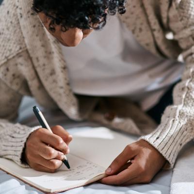 A young man writing on a journal.