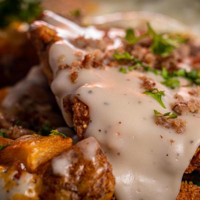 A crispy chicken fried steak with cheesy potatoes, eggs, and gravy.