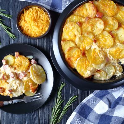 Gratin potatoes in a baking dish and on a plate on a Christmas table.