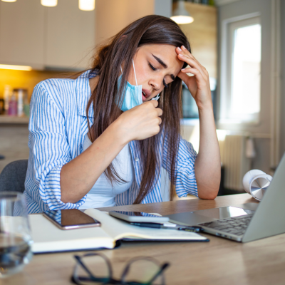 Woman working on a laptop pulls mask down after feeling breathless