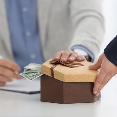 A woman bribing another person in a table in the office.