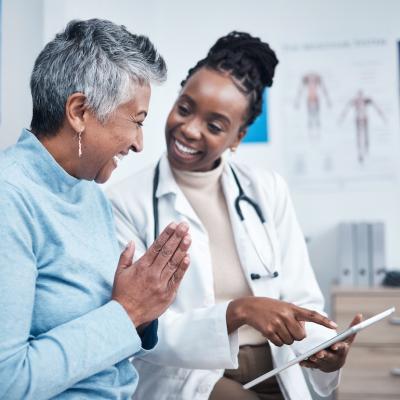 Young doctor reviewing good test results with senior patient on a tablet.