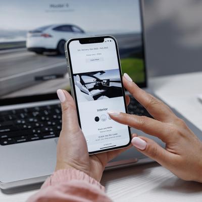 A woman is researching an EV using a laptop and phone.