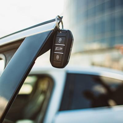 A leased car's key hanging on the edge of an open vehicle door.