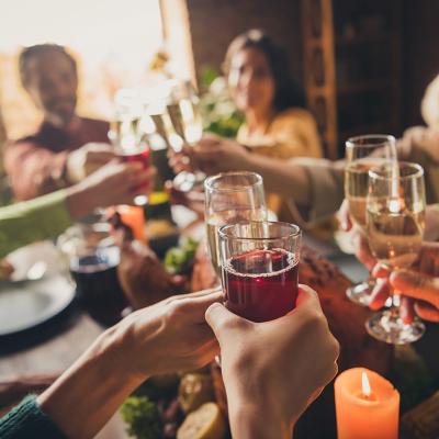 Adults in a family clinking glasses of champagne/wine during a celebration around a table.