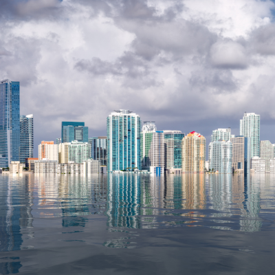 City skyline dots cloudy sky over flooded sea.